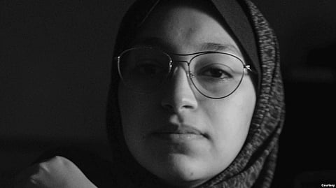 A woman walks past bombed-out buildings in Gaza, in this image captured by Fatima Shbair during the 11-day war in May 2021. Shbair risked her life to photograph scenes from the war. (Photo by Fatima Shbair) Source: voa