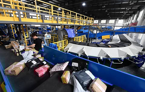 स्वचालित वेयरहाउस लॉजिस्टिक्स सिस्टम जिसमें कन्वेयर बेल्ट और कर्मचारी पार्सल को सॉर्ट कर रहे हैं, आधुनिक ई-कॉमर्स सप्लाई चेन और कूरियर वितरण केंद्र का दृश्य।