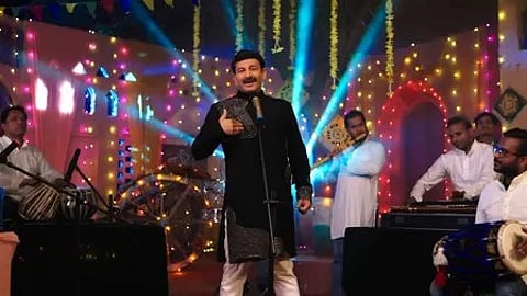 मनोज तिवारी स्टेज पर गा रहे हैं, साथ में दो-चार लोग, बैकग्राउंड में तबला और हरमोनियम बजा रहे हैं|