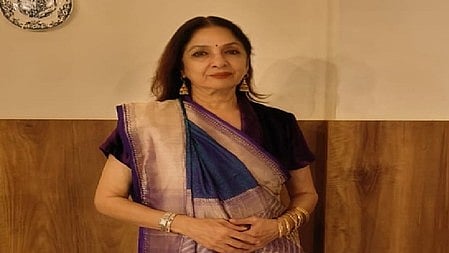 नीना गुप्ता बैगनी रंग की साड़ी पहने खड़ी है