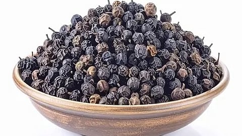 काली मिर्च के दाने एक-दूसरे के ऊपर बिखरे हुए दिखाई दे रहे हैं।