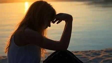 विटामिन B12 की कमी से परेशान महिला सिर पकड़े बैठी हुई|