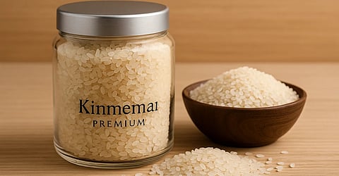 इस तस्वीर में 'किनमेमाई प्रीमियम राइस' नामक चावल दिखाया गया है, जो एक डिब्बे में, एक कटोरी में और थोड़ा नीचे रखा हुआ है।