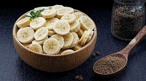 कटे हुए केले एक कटोरी में और चम्मच में काली मिर्च पाउडर|