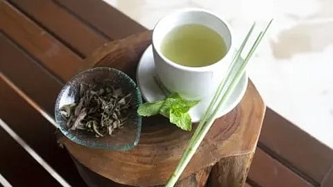 कप में हॉट ड्रिंक और पास में हरी पत्तियां|