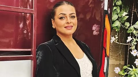 एक लड़की कैमरे के सामने मुस्कुराती हुई नजर आ रही है।