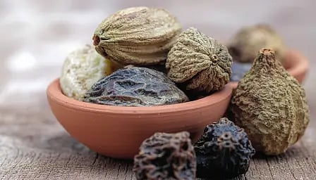 एक कटोरी में रखा हुआ त्रिफला, आयुर्वेदिक जड़ी-बूटी का क्लोज़-अप दृश्य।