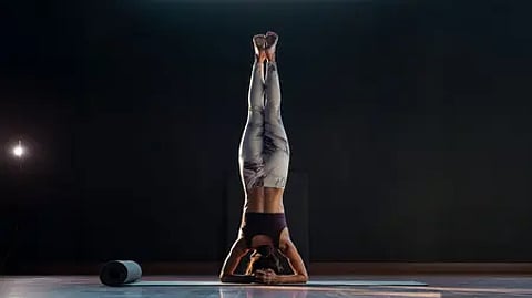 "हैंडस्टैंड करती हुई लड़की, योग अभ्यास में संतुलन और ताकत दिखाते हुए|