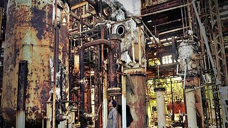 भयानक आग में जलती फैक्ट्री, पास में खड़े व्यक्ति से देखते हुए।