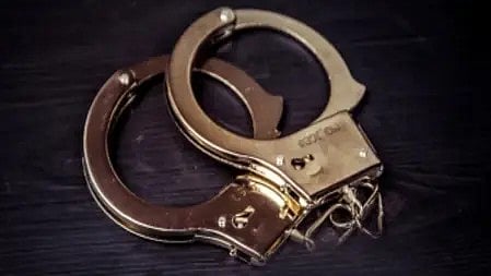 हथकड़ी पहने हुए व्यक्ति का क्लोज़-अप, गिरफ्तारी का प्रतीक|