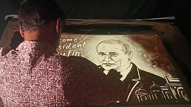 गोल्डन बीच, पुरी में रेत पर रूस के राष्ट्रपति पुतिन की सैंड एनिमेशन तस्वीर बनाते कलाकार का दृश्य|