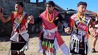 पारंपरिक वेशभूषा में तीन लोग सांस्कृतिक नृत्य करते हुए।