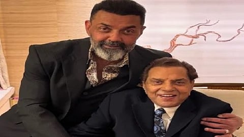 बॉबी देओल और धर्मेंद्र साथ बैठे हुए, पिता-पुत्र का भावुक पल।