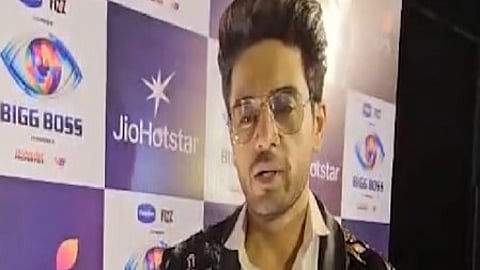 इस तस्वीर में गौरव खन्ना कुछ बोलते हुए नज़र आ रहे है, इन्होंने अपने आँखो पर चस्मा पहना है और ब्लैक कोर्ट और सफ़ेद शर्ट पहने है।