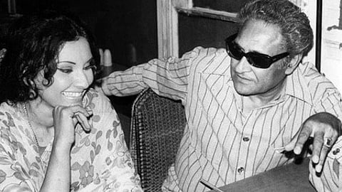 एक आदमी और एक महिला बैठे हुए बातचीत करते हुए नजर आ रहे हैं।