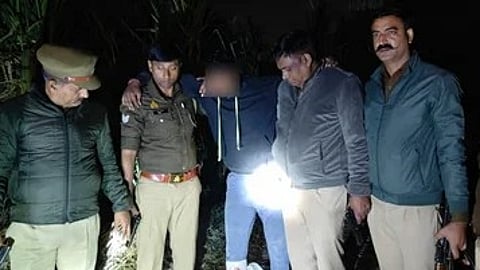 मुठभेड़ के बाद गिरफ्त में खड़ा एक आरोपी, जिसके आसपास पुलिसकर्मी मौजूद हैं।