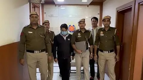 चार पुलिसकर्मी एक क्रिमिनल को पकड़े हुए खड़े हैं।