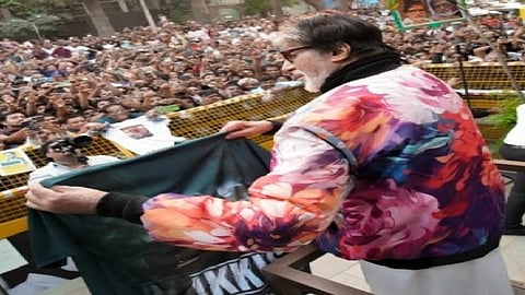 भीड़ के सामने मंच से फिल्म क प्रसार करते हुए एक अभिनेता, हाथ में पोस्टर लिए हुए।