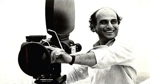 एक व्यक्ति सिनेमैटोग्राफी कैमरा लिए खड़ा|