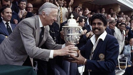 कपिल देव और अन्य व्यक्ति ट्रॉफी लेते हुए|