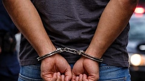 इस इमेज में एक आदमी के हाथों में हथकड़ी को देखा जा सकता है।