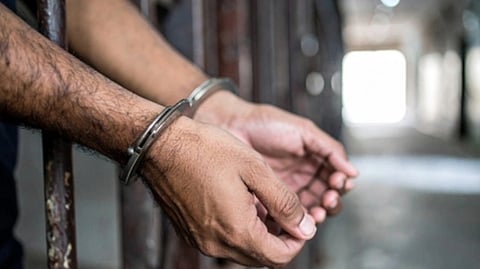 इस इमेज में एक हथकड़ी से हाथो को बंधा हुआ देखा जा सकता है।