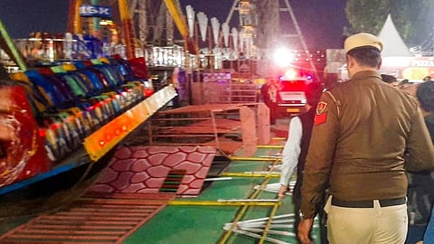 मेले में गिरे हुए झूलों को देखा जा सकता है जहाँ एक पुलिस अफसर भी खड़ा है।