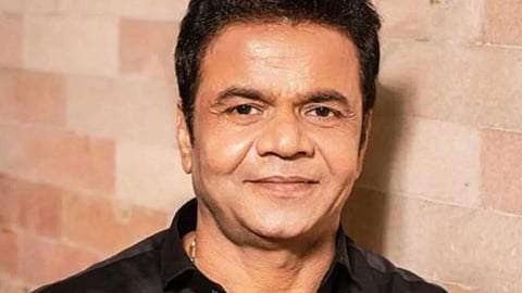 काले रंग की शर्ट में सामने की ओर देखते अभिनेता राजपाल यादव