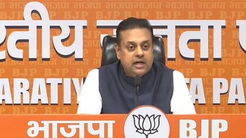 बीजेपी के नेता ब्लू जैकेट और सफ़ेद कुर्ता में माइक के सामने बोलते हुए