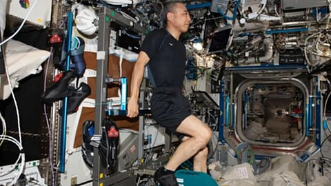 अंतरिक्ष यान में एक व्यक्ति जो काले कपड़ों में लेटा दिखाई दे रहा है।