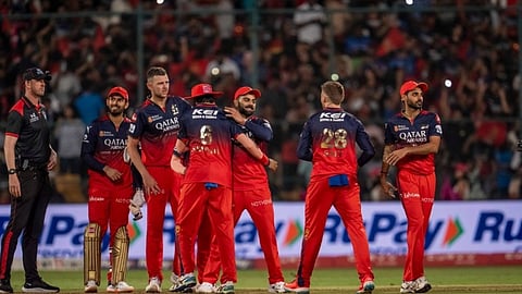 मैदान पर रॉयल चैलेंजर्स बेंगलुरु (RCB) के खिलाड़ी लाल और काली जर्सी में एक विकेट गिरने के बाद जश्न मना रहे हैं।