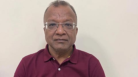 लाल रंग का टी शर्ट पहने एक व्यक्ति जो गंभीर मुद्रा में नज़र आ रहा है