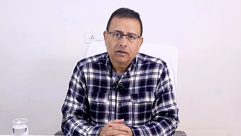 कैमरे के सामने देखकर बोलते डॉ. मुनीश कुमार रायज़ादा, गंभीर मुद्रा में नज़र आ रहे हैं।