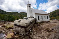 Hurricane Helene Kills Over 200 | Photo: AP/Mike Stewart : Hurricane Helene: A bus pushed by flood waters rests against Laurel Branch Baptist church