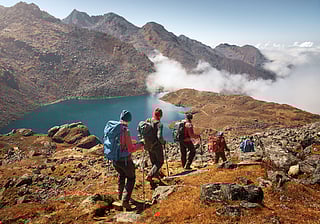 Group of tourists descends down a mountain trail to a lake during a hike in the national park Lantang, Nepal
