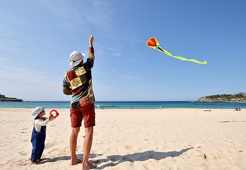 Daughter and father flying a kite on Bondi Beach in Sydney, Australia