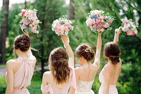 Bridesmaids in pink dresses and bride holding beautiful bouquets