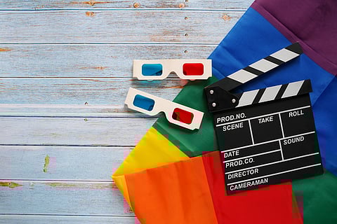 A pride flag with a film clapperboard and 3D glasses