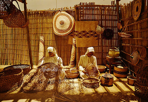 A display gallery showing artisans weaving baskets, one of the many souvenirs you can buy in Bahrain, at the Bahrain National Museum in Manam
