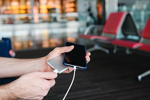 Traveller using a power bank inside an airport terminal before a flight