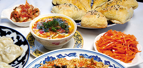 An Uzbeki spread with manti dumplings, shurpa, somsa, rice plov, and pickled vegetables