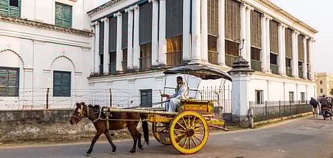 A horse cart rides past the exterior facade of the ancient Nizamat Imambara in the old town of Murshidabad