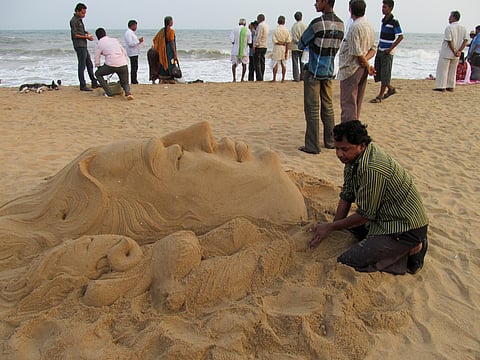 An artist works on a sand art sculpture on Chandrabhaga beach in Odisha