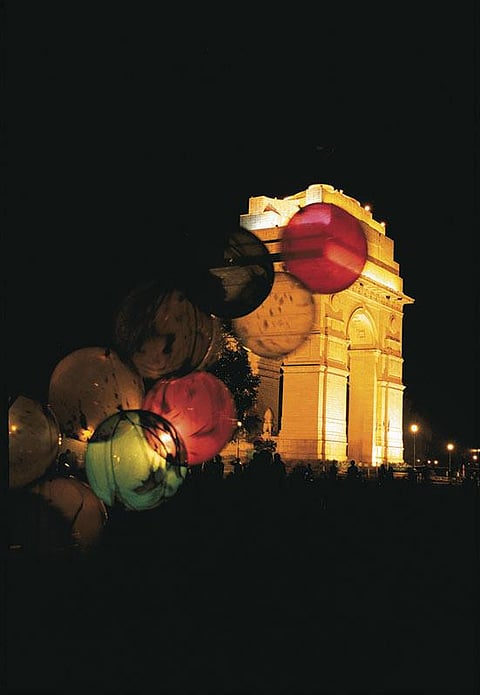 A brightly lit India Gate at night