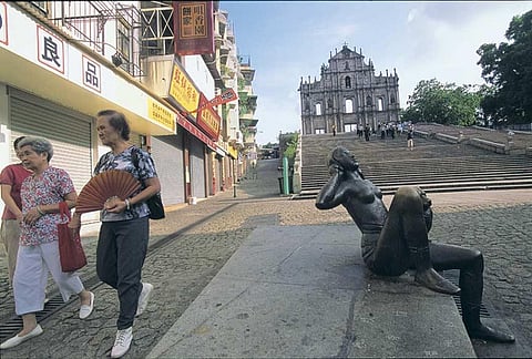 Tourists walk past the ruins of St Paul, Macau