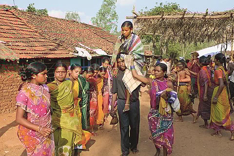 Women dance in a circle as the bride is carried on her father's shoulder