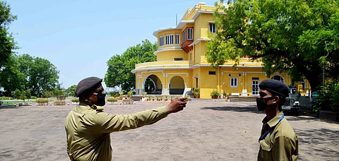 A security guard thermal screens a staff member as he returns from the market at Brijraj Bhawan Palace Hotel