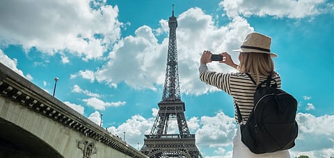 A tourist taking a picture near the Eiffel Tower