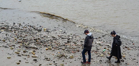 People walking along the polluted shoreline of the Thames