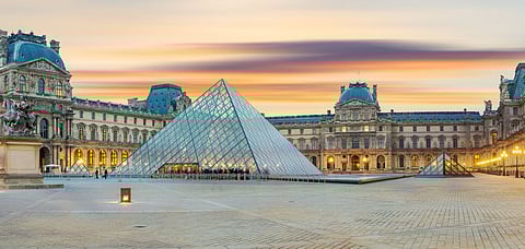 View of famous Louvre Museum with Louvre Pyramid at sunrise.